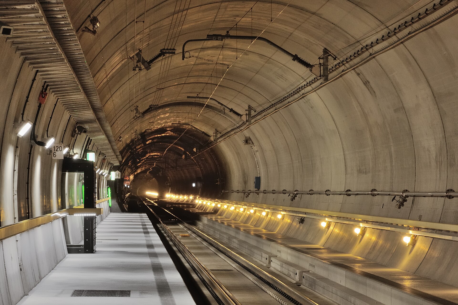 Lange rechte tunnelbuis met sporen, bekabeling en verlichting